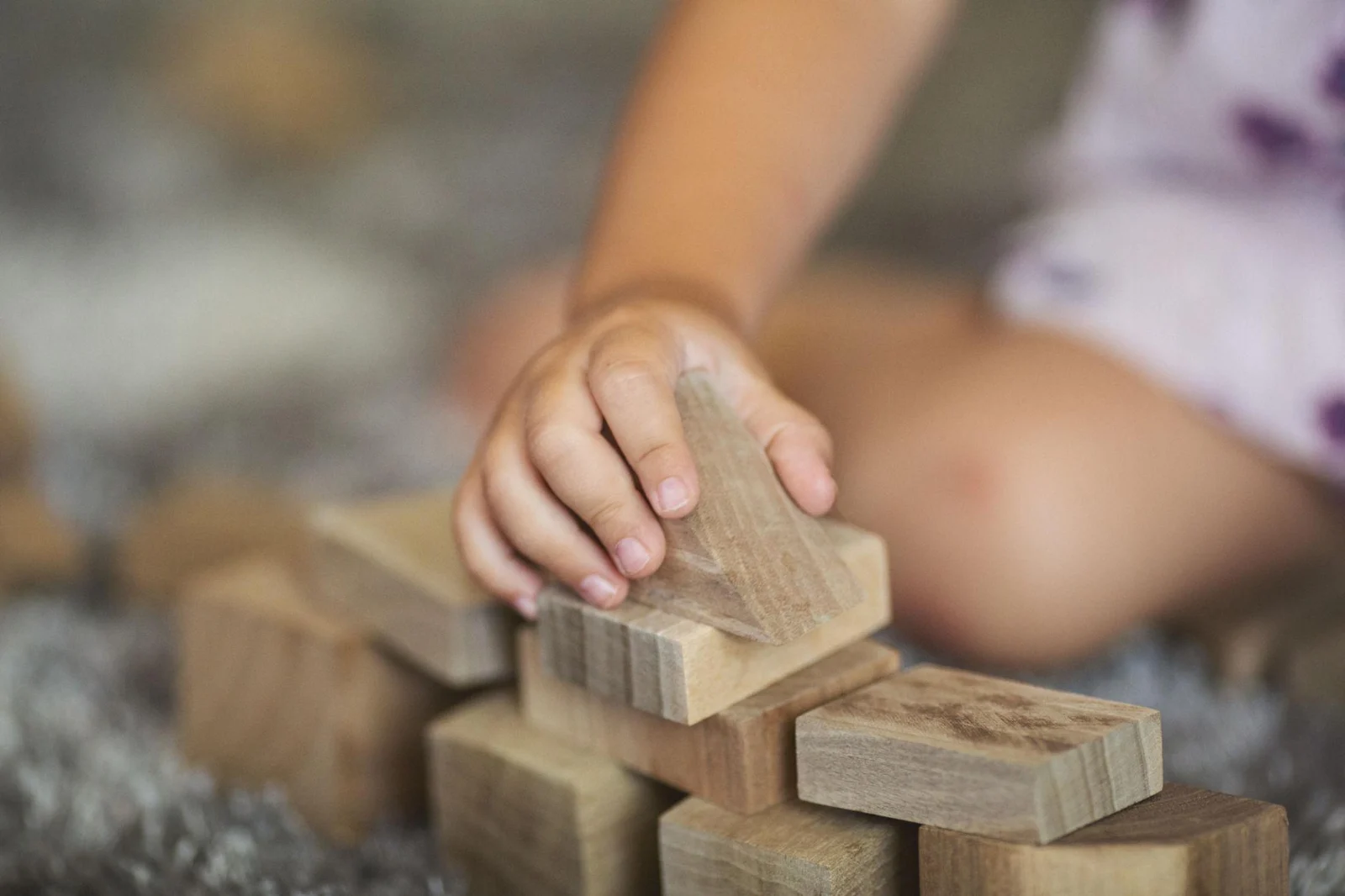 A child’s hand carefully balancing a wooden block